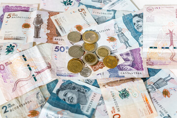 Macro closeup of Colombian peso coins on banknotes of different denominations