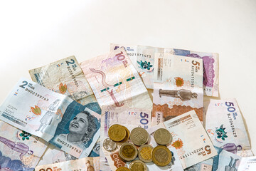 Macro closeup of Colombian peso banknotes and coins on white background