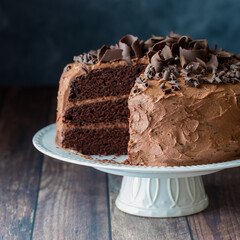 A triple layered moist chocolate cake with frosting and chocolate curls.