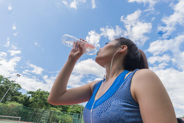 beautifull sport girl drinking water at the tennis court and wearing blue sport bra