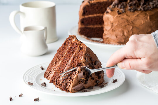 Cutting into a piece of moist homemade low sugar chocolate cake with a fork.