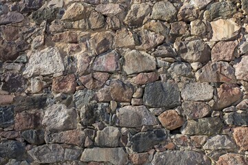 Weathered old rock wall with big and small stones.