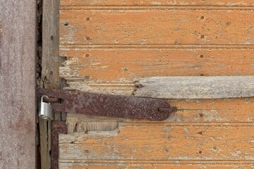 New padlock with rusty latch on a old wooden door.