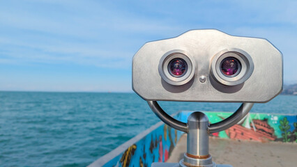 Watching black sea through binoculars telescope. travel and tourism. Coin-operated binocular at...