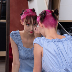 Fototapeta premium teenager girl looks in the mirror in the studio, carefully examines her face
