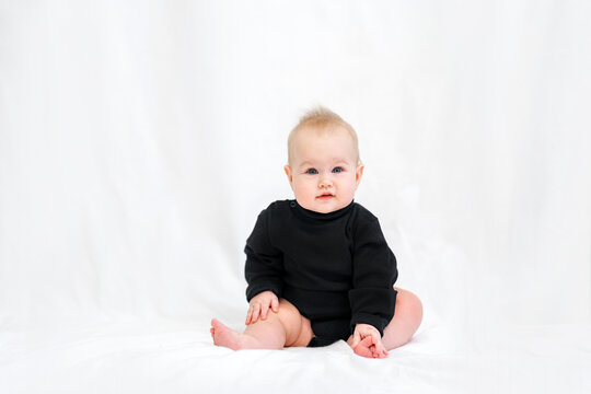 Portrait of a charming Caucasian baby in a stylish black bodysuit on a white background