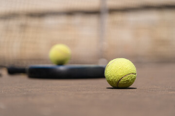 From above closeup of yellow padel balls placed on court near racket on sunny day