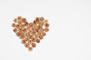 Walnuts are laid out in shape of heart on white background. Flat lay, top view, copy space 