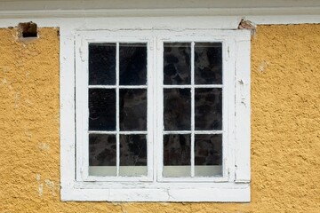 White wood framed window on a old yellow painted plastered building.