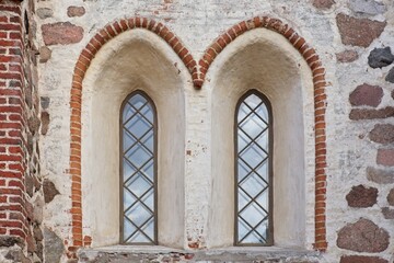 Obraz premium Wood framed glass windows on a decorative old building made of stone and bricks.