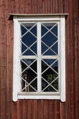 White painted wood framed window on a old red wooden building.