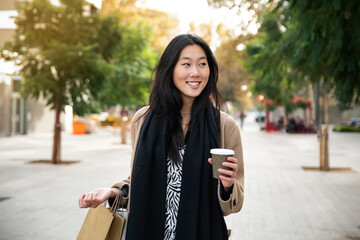 Young beautiful woman with a cup of coffee and shopping bag in the city - fasion concept