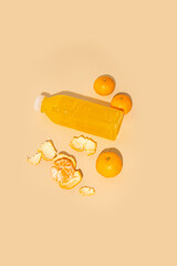 Detox drink in a plastic bottle, tangerines on a beige background. top view, flat lay.