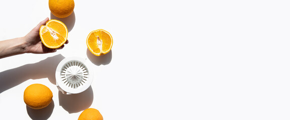 Female hand squeezes juice from oranges in a hand bowl on a white background. Top view, flat lay....