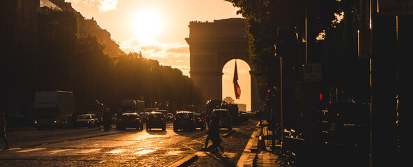 The iconic Arc de Triomphe stands tall in the background as cars venture into the stunning sunset...