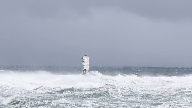 the lighthouse of the mangiabarche in calasetta, in southern sardinia, submerged by the waves of the stormy sea
