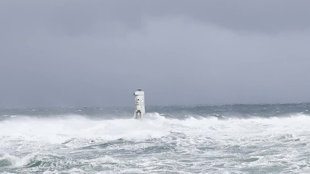 the lighthouse of the mangiabarche in calasetta, in southern sardinia, submerged by the waves of the stormy sea
