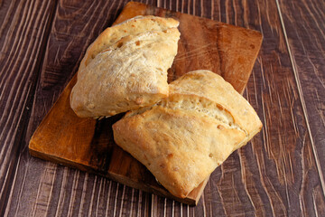 Two rustic rolls on a wooden serving board. Close-up. 