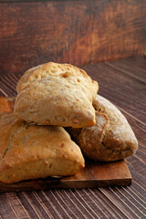Three rustic rolls on a wooden serving board. Close-up. 