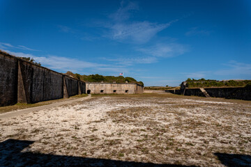 Fototapeta na wymiar Gulf Islands National Seashore along Gulf of Mexico barrier islands of Florida. Fort Pickens pentagonal historic United States military fort on Santa Rosa Island. Counter scarp dry moat and flag. 