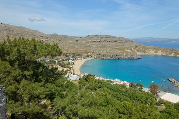 Obraz premium View of Lindos beach seen from ancient acropolis of Lindos and medieval castle in sunny spring weather, Rhodes, Greece.