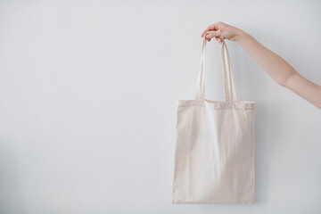 White blank cotton tote bag against a white wall. Reusable eco bag. Eco friendly concept. Mockup.