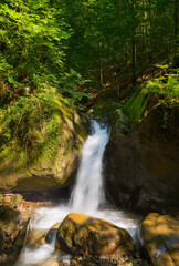 waterfall on the creek out of boulders. summer nature scenery in the forest. refreshment on a hot summer day