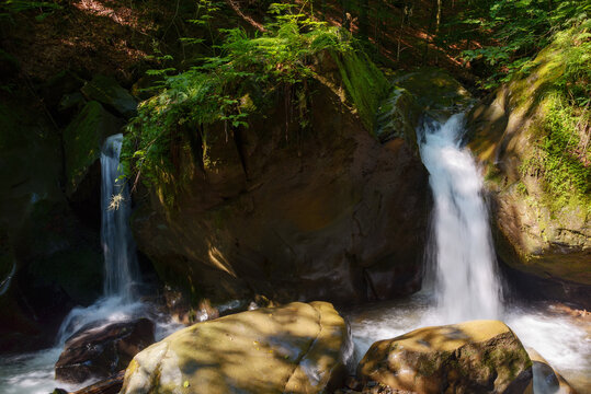 waterfall on the creek out of boulders. summer nature scenery in the forest. refreshment on a hot summer day