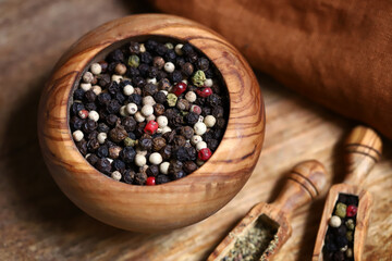 Mix of peppercorns in a wooden mortar and wooden spatulas.