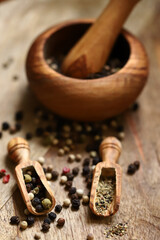 Mix of peppercorns in a wooden mortar and wooden spatulas.