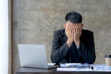Asian businessman is stressed and eye strain and tired due to long working day on laptop computer at work.