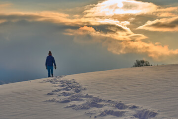 nice and active senior woman snowshoeing in deep powder snow during sunset in the mountains of the Bregenz Forest  Alps near Sulzberg, Vorarlberg, Austria
