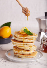 Stack of Pancakes with lemon flavor and poppy seeds, served with honey. Healthy breakfast for the family. 