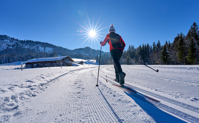 beautiful active senior woman cross-country skiing in fresh fallen powder snow in the Allgau alps...