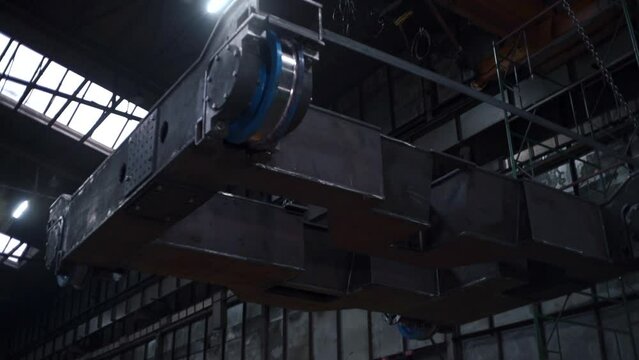 Metal construction on suspensions at factory. Clip. Suspension systems with anchors for carrying loads at factory. Automated movement of heavy structures at factory