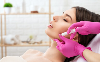 Cosmetologist makes rejuvenating anti wrinkle injections on the face of a beautiful woman. Female...