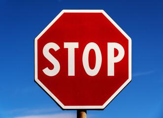 STOP ROAD SIGN WITH A BLUE SKY BACKGROUND