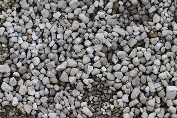 Gray raw rocks and rough stones as natural stones background with crushed and rough material as building material or rocky base for concrete mixture in gray colors as natural stones background
