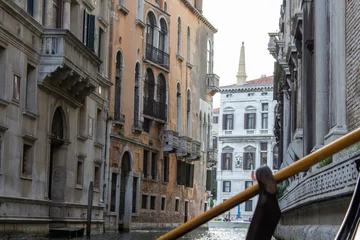 Fotobehang A view from a gondola capturing the ancient architecture along a narrow Venetian canal, showcasing the city's timeless charm and romantic atmosphere. © Keifer