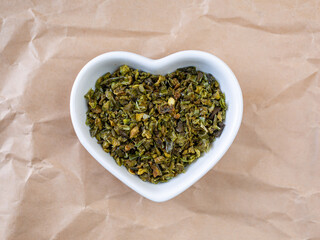 Dried green paprika slices in a heart shaped white bowl