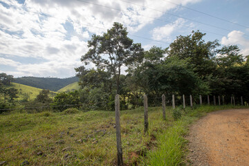 Fototapeta na wymiar dirt road with wooden fence and barbed wire in countryside of Sao Paulo state, Brazil