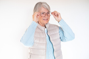 Portrait of attractive senior woman isolated on white background touching her glasses. Close up face of smiling mature lady with white hair enjoying retirement.