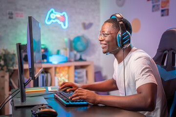 Streamer young man professional gamer play online games computer with headphones, colorful neon room