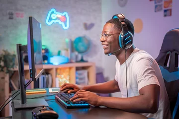 Fotobehang Gaming Streamer young man professional gamer play online games computer with headphones, colorful neon room  © LiettaOraz