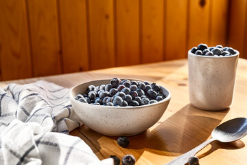 Fototapeta na wymiar Fresh organic blueberries. Juicy ripe bilberry in white bowl on wooden table. Antioxidant and healthy eating concept.