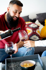 Man pouring wine in a glass for his partner