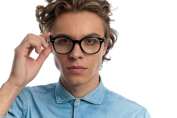 casual man adjusting his eyeglasses with serious face