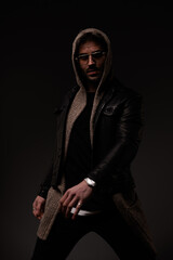 Fototapeta na wymiar fashion man with beard wearing leather jacket and posing in a cool manner