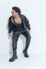 Fototapeta premium cool muscle guy with curly hair wearing leather suit and looking to side