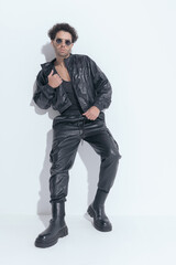 Fototapeta premium handsome sexy man with sunglasses fixing leather jacket